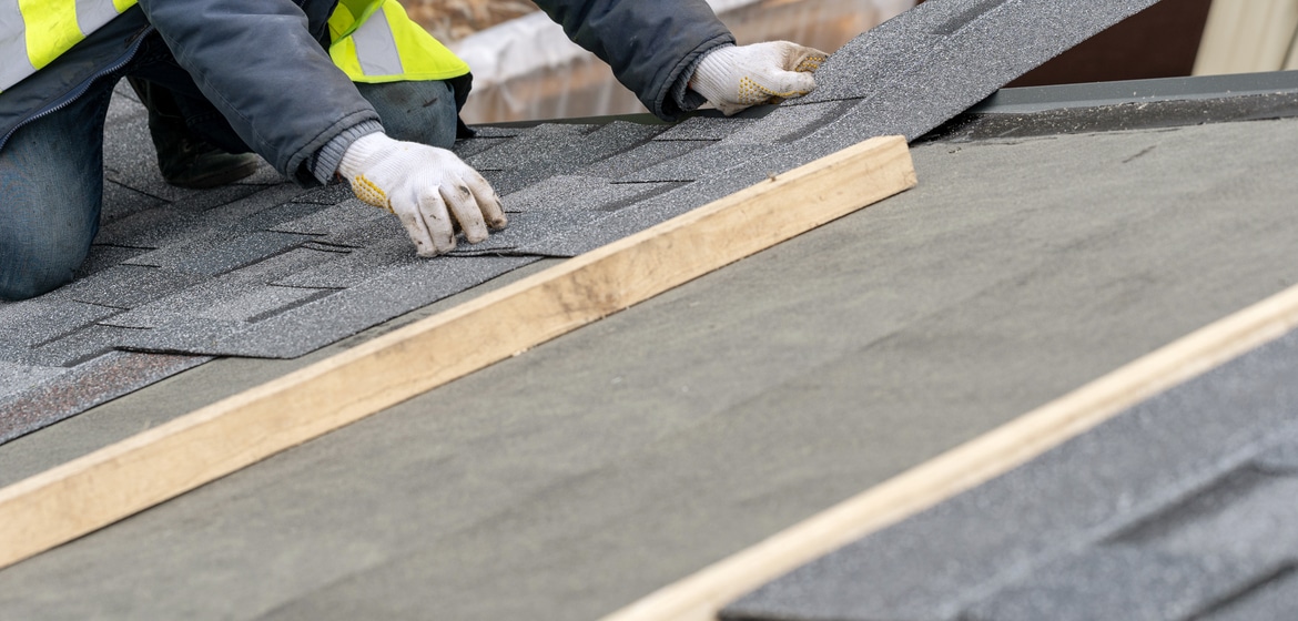 Workman install tile on roof of new house under construction